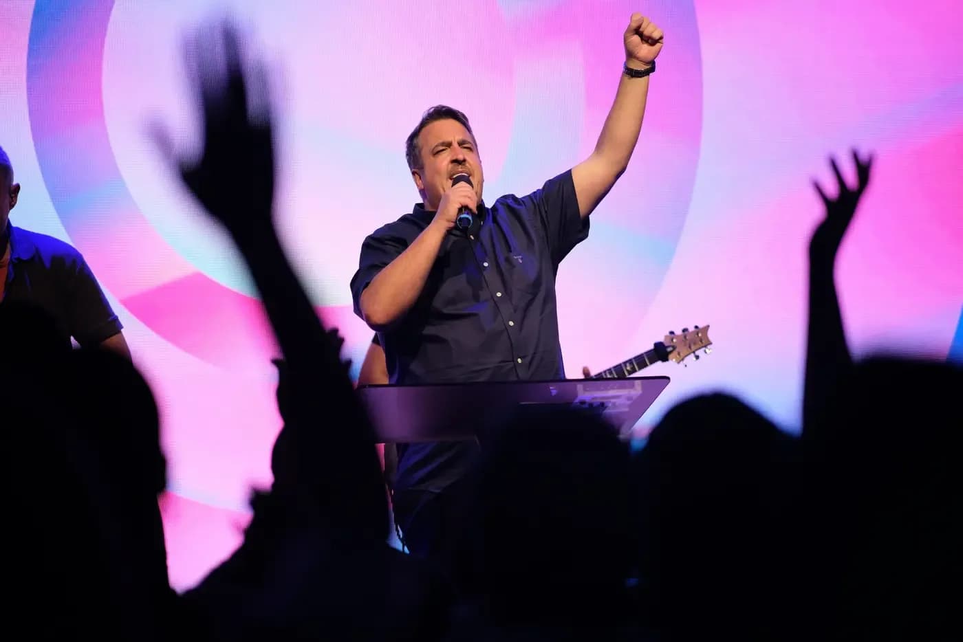 Worship service at Elim Pentecostal Wimbledon with worship leader singing and congregation raising hands