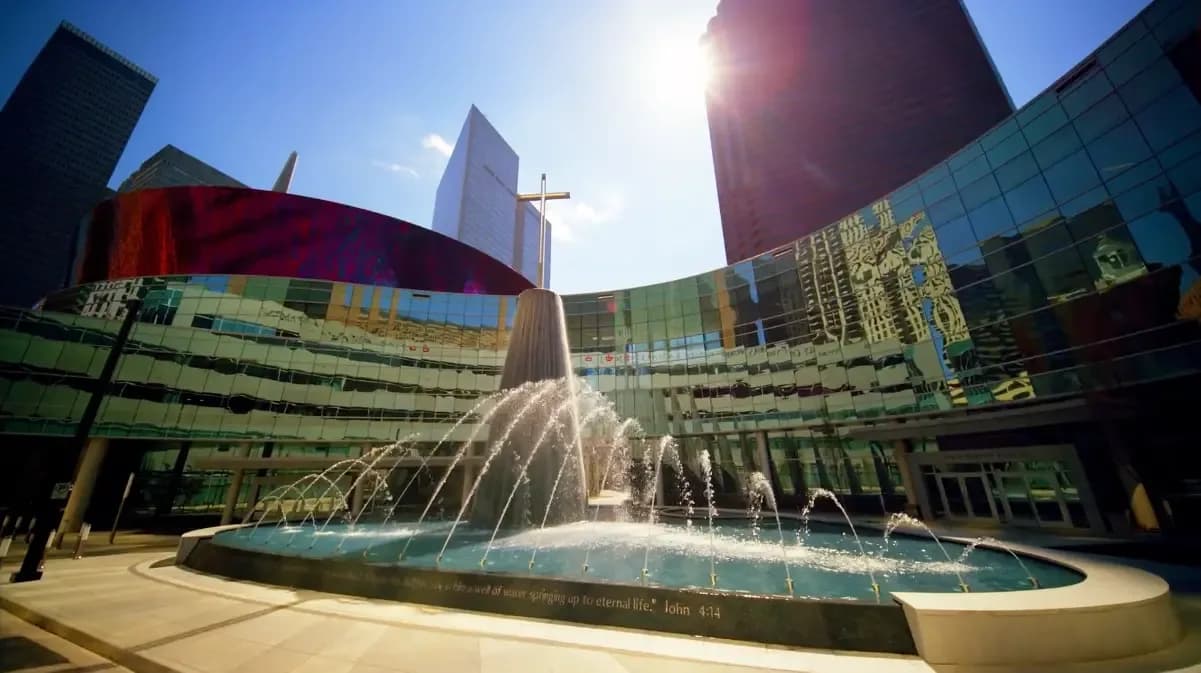 Exterior of First Baptist Dallas featuring the outdoor fountain, cross, and glass building facade in downtown Dallas