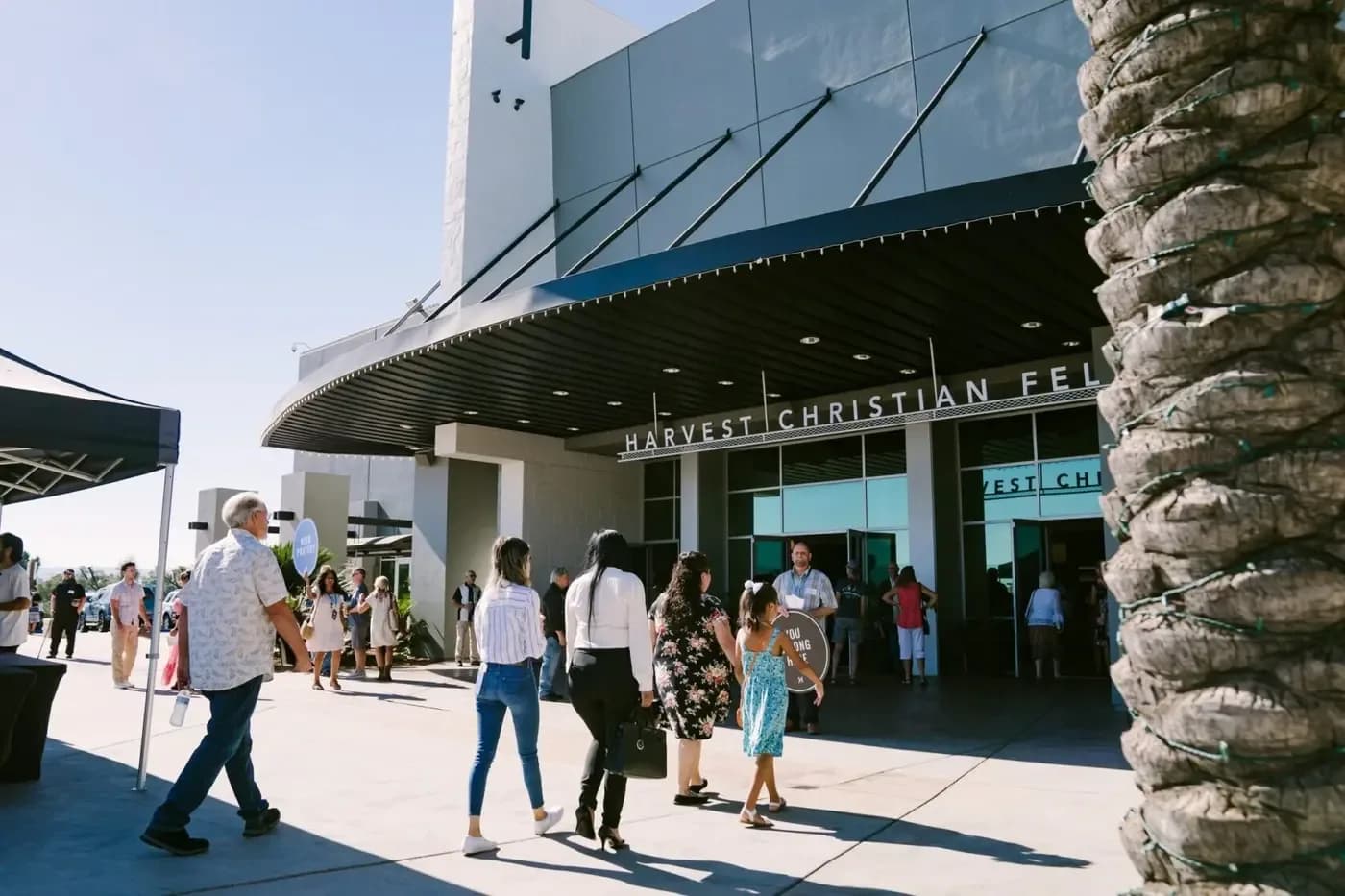 Exterior entrance of Harvest Christian Fellowship with the church name visible above the doors as people arrive