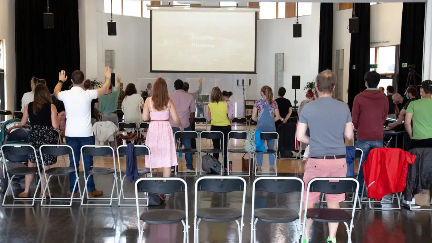 Congregation worshipping with raised hands in a ChristChurch London worship space