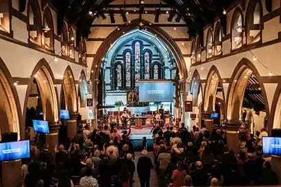 Interior of All Saints' Woodford Wells during a worship service with congregation gathered under gothic arches