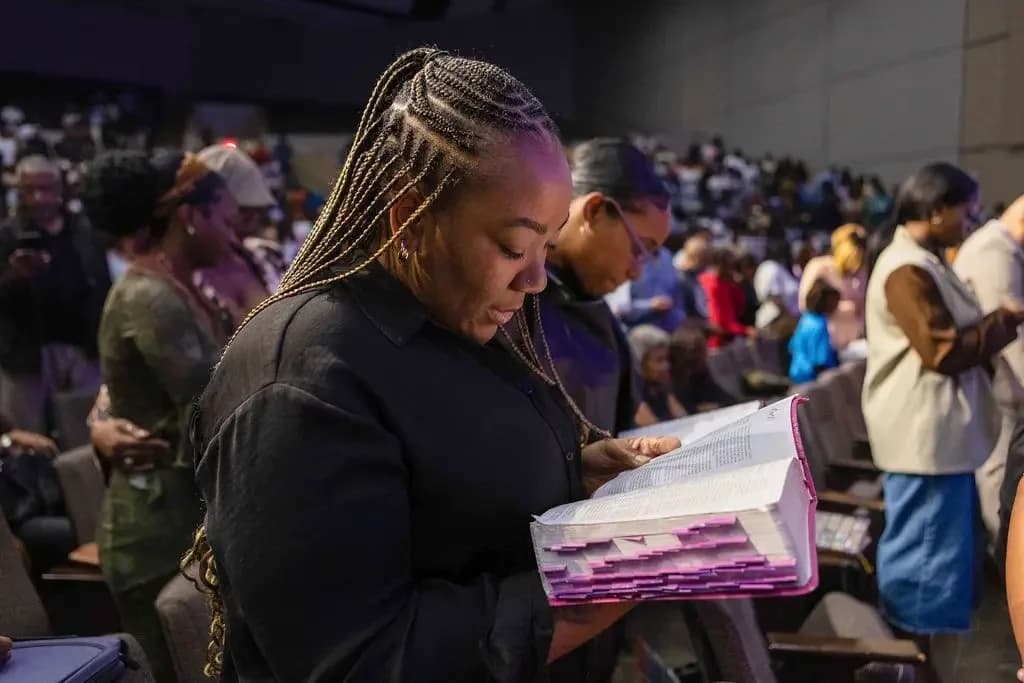 Congregation standing in worship at Concord Church, a woman reading her Bible during service